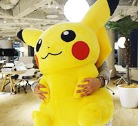 Atsuko Nishida hiding behind a giant Pikachu plush during her official interview